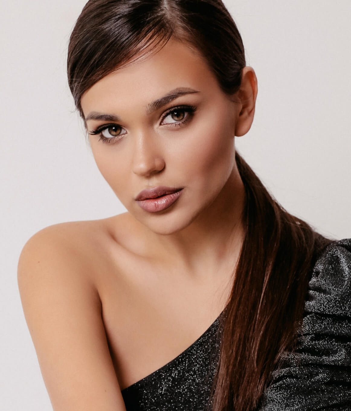 woman wearing a black off the shoulder dress against a white background