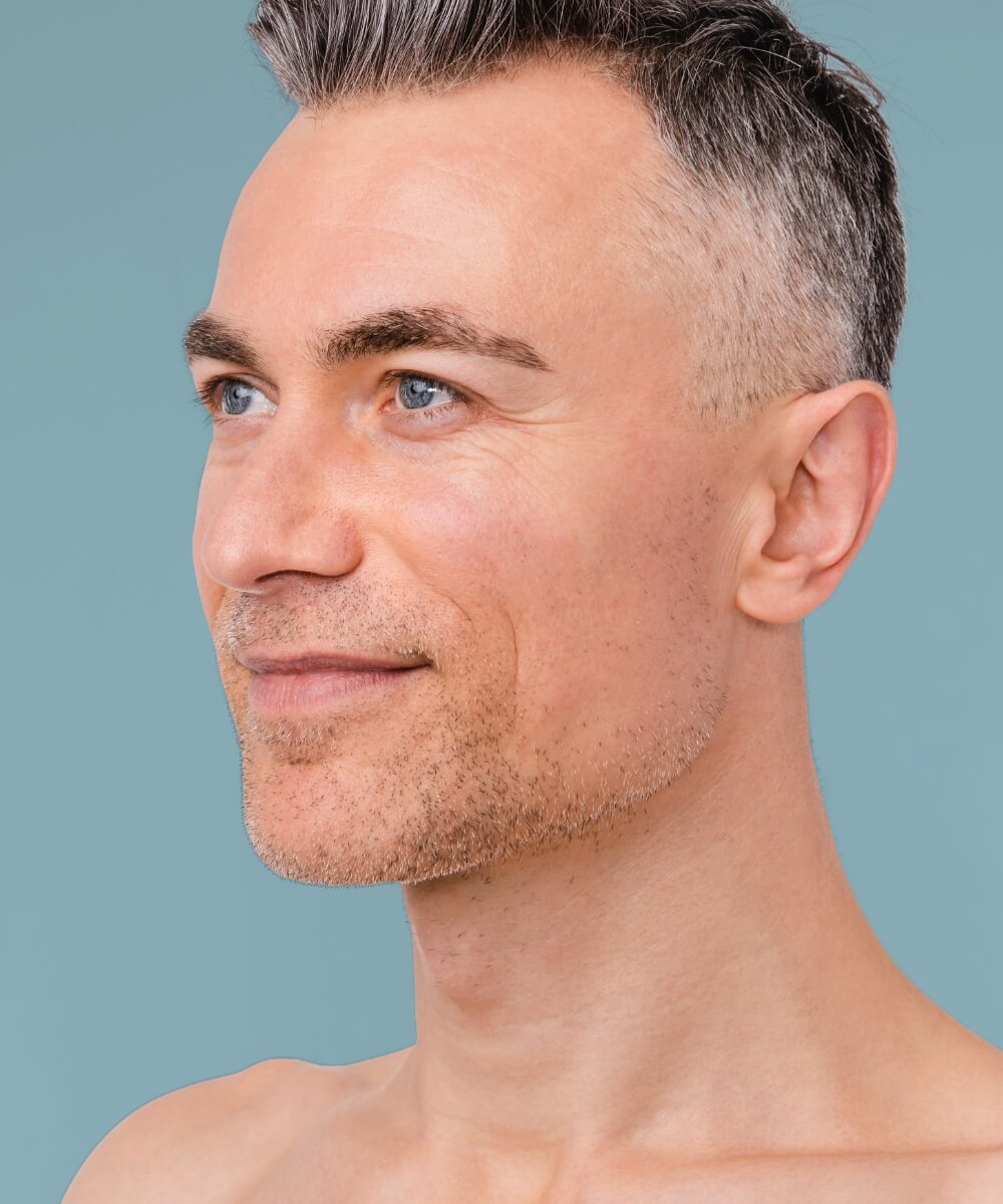 man in oblique view with black and grey hair smiling softly